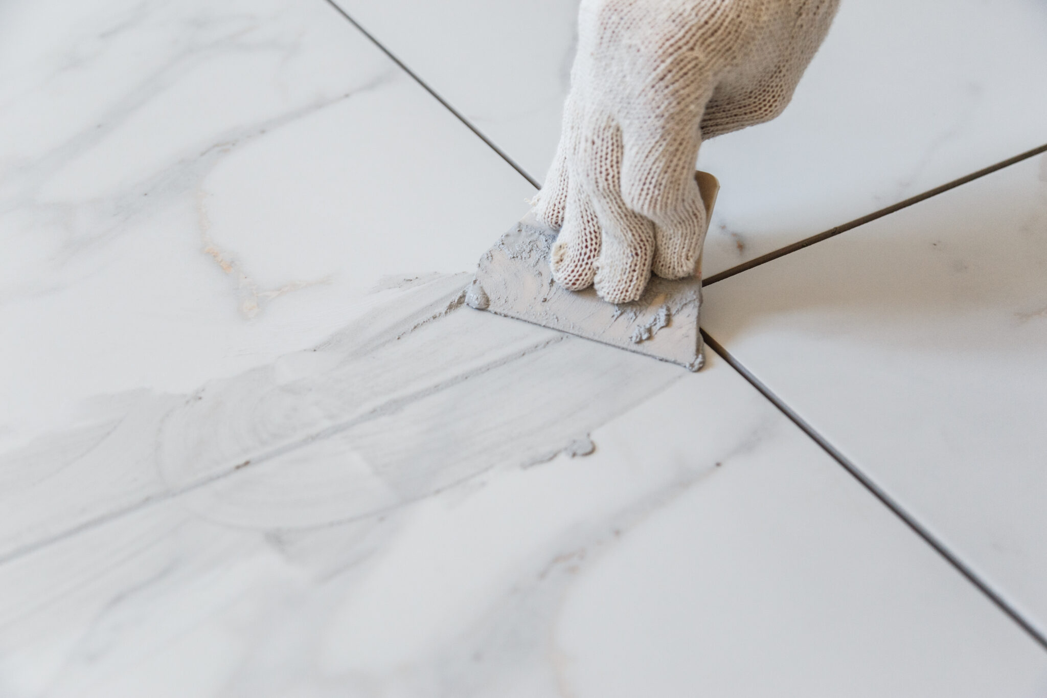 Hand applying grout to marble tiles.