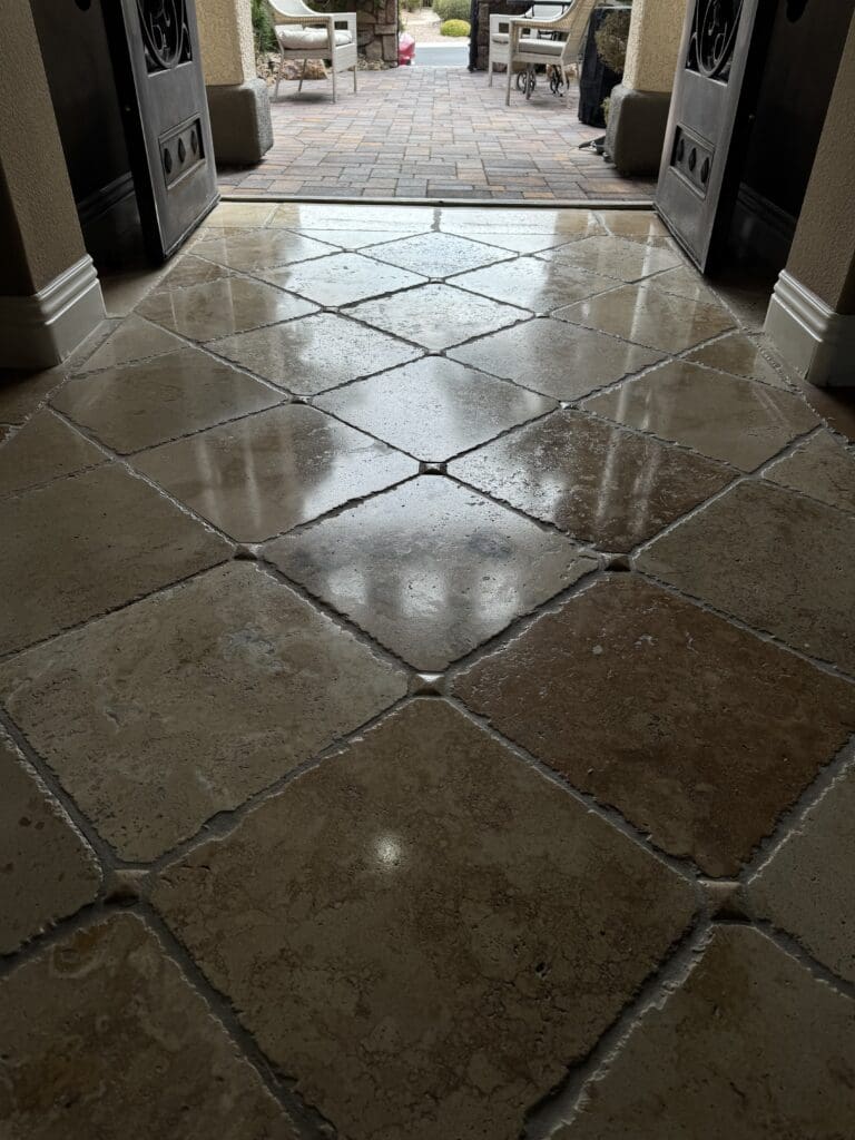 Polished travertine floor showcasing smooth, glossy tiles in an entryway, highlighting the restoration and shine achieved through professional travertine polishing services in Las Vegas.